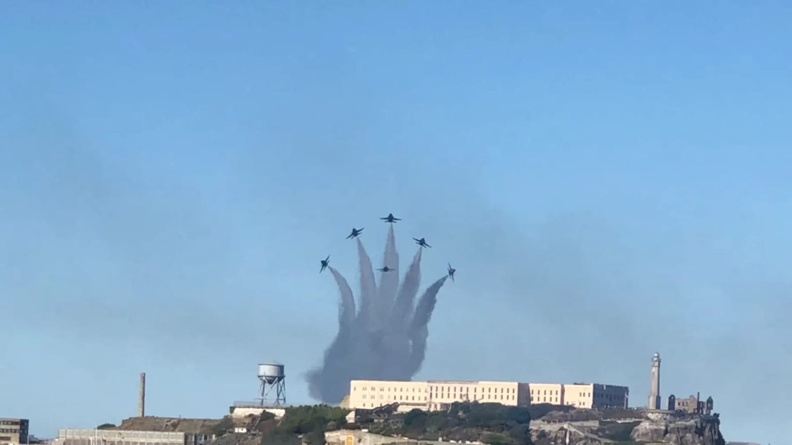 Blue Angels jets in delta formation trailing smoke above Alcatraz Island