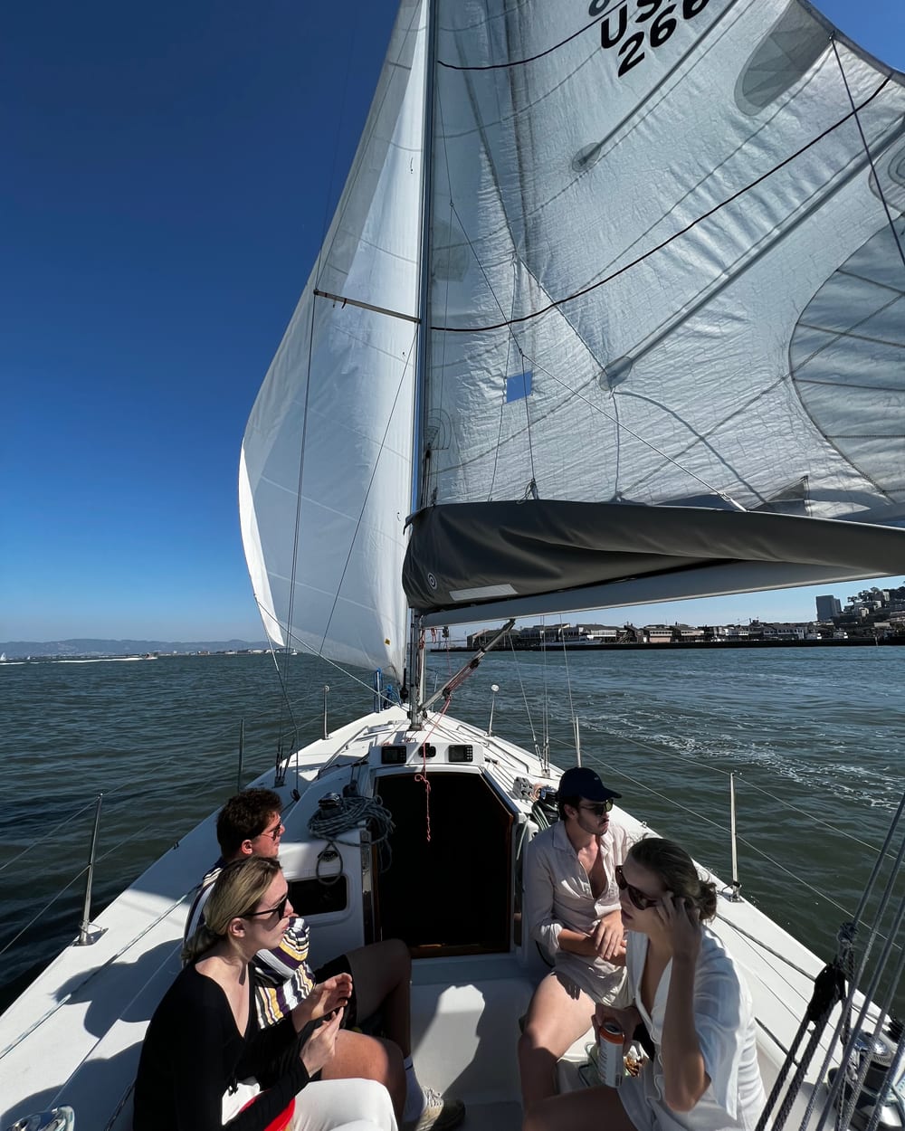Guests in light summer clothes relaxing in the cockpit of the J/105 Wonder under full sail, with deep blue sky above