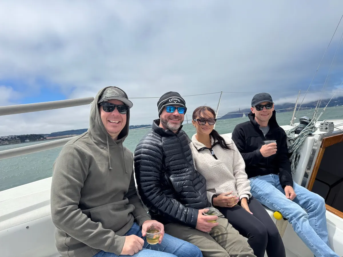 Four guests sitting in the cockpit with drinks in hand, the Golden Gate Bridge behind them