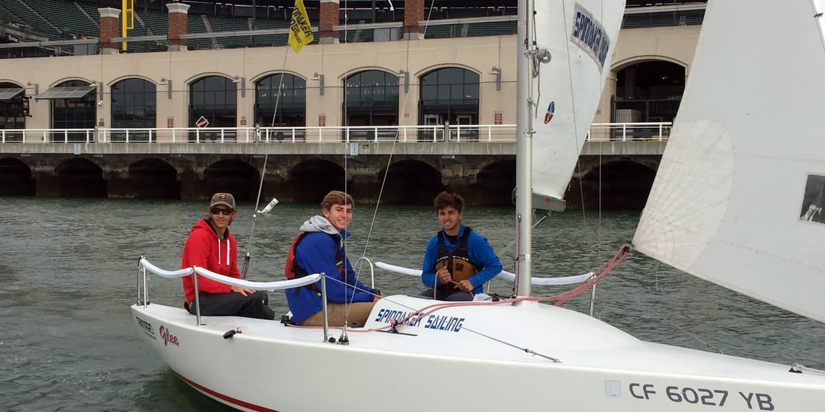 Sailing students aboard a Spinnaker Sailing J/80 beside Pier 40 in San Francisco
